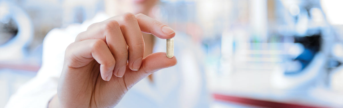 Doctors hand holding one capsule